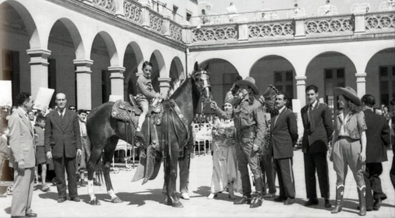 Imatge en blanc i negre amb Buffalo Bill i un nen montat en un caball